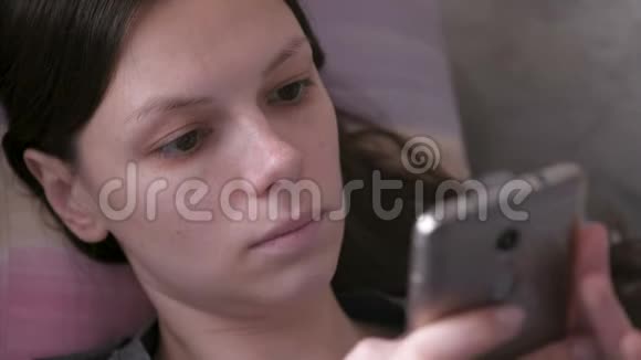 悲伤的女人躺在沙发上在手机上读着什么特写的脸视频的预览图