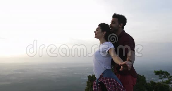 两人在山顶拥抱举起双手快乐的拉丁男女享受自由之风视频的预览图