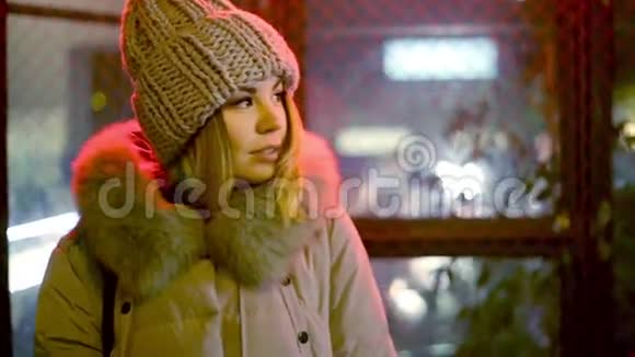 年轻的亚洲女孩正等在一个篱笆墙的背景上红色的灯光看着镜头视频的预览图