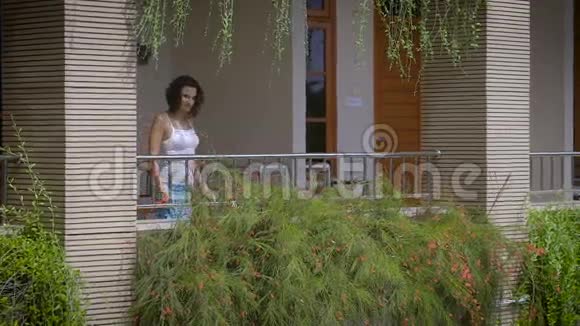 美丽的黑发女郎走在她的热带私人别墅阳台上呼吸着清新的巴厘岛空气青年视频的预览图
