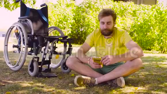 快乐的残疾青年坐在公园的草地上视频的预览图