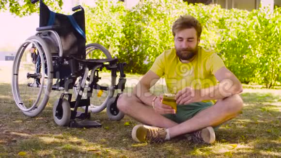 快乐的残疾青年坐在公园的草地上视频的预览图