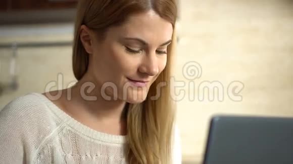 美丽的年轻迷人的女人吃早餐在厨房里用笔记本电脑工作视频的预览图