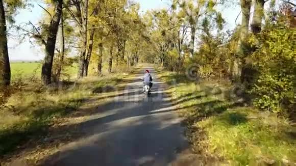 在黄秋林里的路上小巷和男孩骑着摩托车视频的预览图