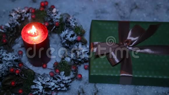 圣诞礼物上面有一条棕色的丝带上面有人工雪和点燃的蜡烛视频的预览图