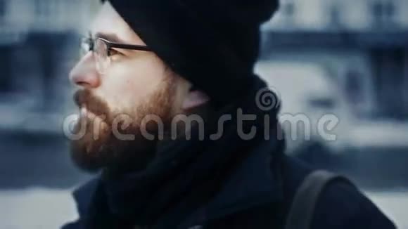 戴着帽子戴着眼镜的白种人在冬天的街道上转过头来视频的预览图