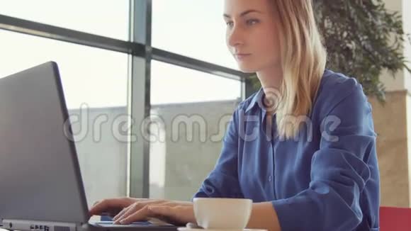 快乐的年轻女子在咖啡店里喝咖啡和使用平板电脑视频的预览图
