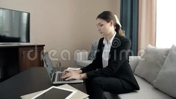 一位年轻漂亮的商务女性在酒店的男式西装房里用电脑工作视频的预览图