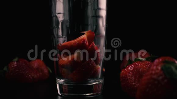 在玻璃杯中切好的草莓由鸡尾酒倒入慢动作视频的预览图