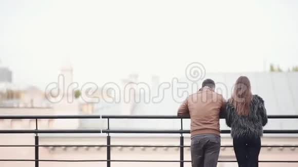 一对夫妇站在一座城市的屋顶上他们欣赏风景在街上往下看视频的预览图