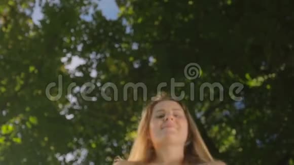 幸福微笑的年轻女子俯下身子看花园里的摄像机的画像视频的预览图