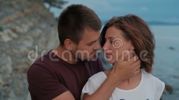 夏天晚上年轻人亲吻坐在海边的女人视频的预览图