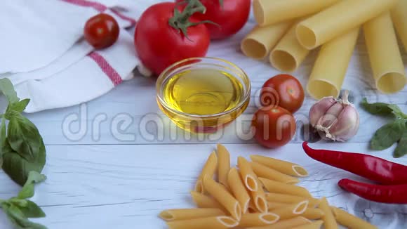 白色木桌上的橄榄油番茄酱罗勒和各种面食视频的预览图