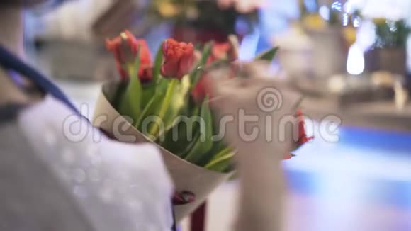 女花店手把红玫瑰放进锥形盒子后景视频的预览图