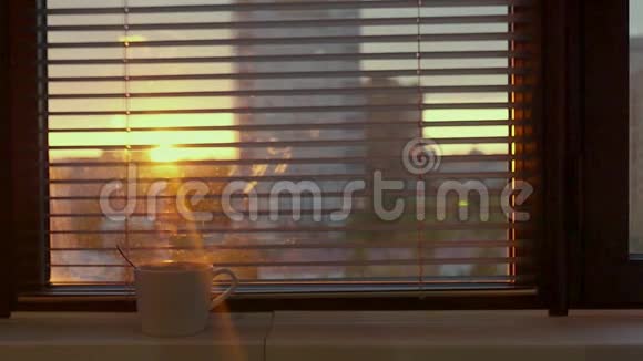 蒸汽在一杯热茶里抽着烟站在靠近窗户的窗台上可以看到城市和一个视频的预览图