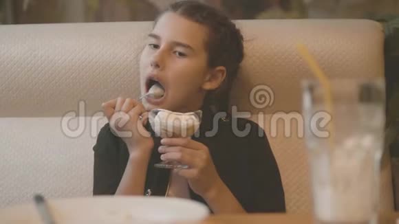 小女孩在快餐店吃冰淇淋慢动作视频孩子在咖啡馆吃冰淇淋有趣的卷发孩子视频的预览图