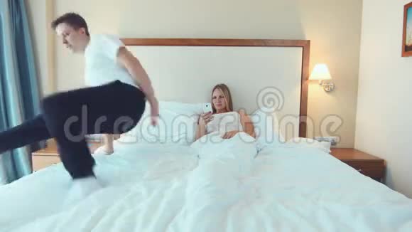 女人在床上用电话在男人旁边视频的预览图