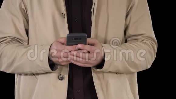 穿风衣的人使用移动智能手机阿尔法频道视频的预览图