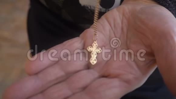 老妇人把基督教十字架放在手掌上视频的预览图