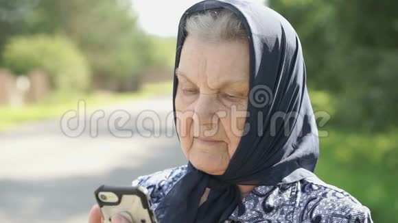 微笑成熟的老妇人在户外展示智能手机视频的预览图