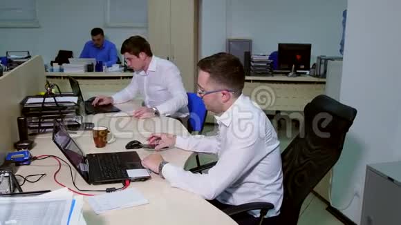 两个商人在一间办公室里用台式电脑工作视频的预览图