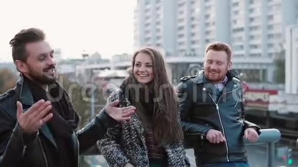两个英俊的年轻人和一个漂亮的女孩站在城市的桥上谈笑风生斯泰迪加姆慢点视频的预览图