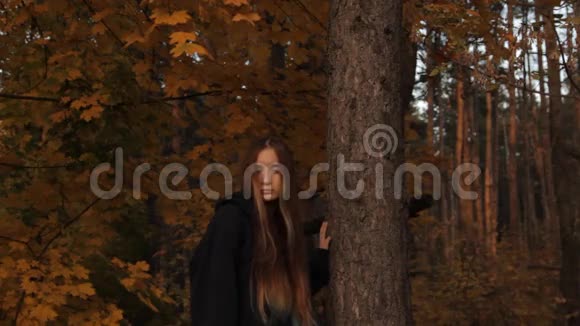 一个头戴帽衫头发松松的女孩用手扶着一棵树闷闷不乐地环顾四周一个中锋视频的预览图