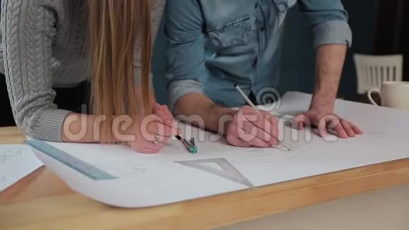 年轻的女人和男人是一个建筑师在办公室里工作蓝图笔记本电脑和房子模型视频的预览图