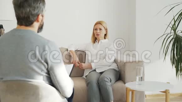 患有抑郁症的成年压力妇女在室内心理治疗办公室与男性专业精神分析人员交谈视频的预览图