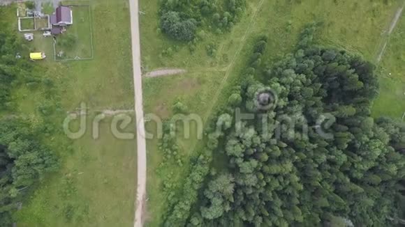 夏季穿过田野和森林的乡村道路的空中俯视剪辑带道路的林区俯视图视频的预览图