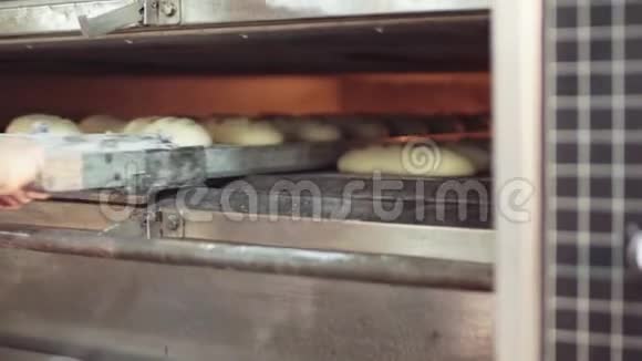 用男性手将未烤好的面包放进烤箱准备健康食品面包厂视频的预览图