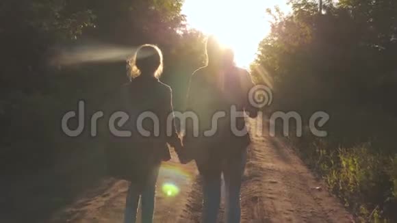 徒步旅行者女孩带着背包的快乐女孩旅行者牵着手在明亮的阳光下沿着乡间的道路奔跑概念视频的预览图
