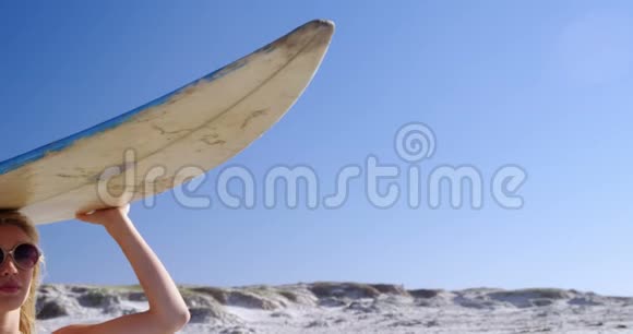 头上拿着冲浪板的年轻女子视频的预览图