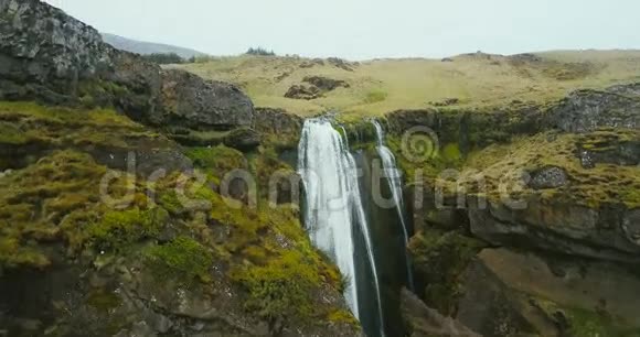 冰岛瀑布的鸟瞰图直升机飞过绿色的山谷和河流坠落视频的预览图