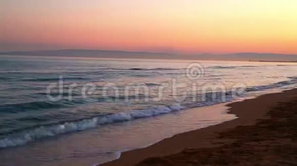 一片平静的黄昏海在海湾中波浪日落背景上有一个沙滩时间跨度视频的预览图