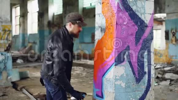英俊的胡子男涂鸦艺术家正在废弃的建筑里用喷漆作画现代街头艺术青年视频的预览图