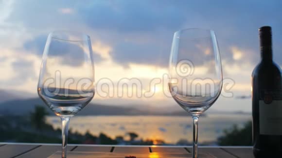 两杯酒和一瓶酒站在天空背景日落的桌子上视频的预览图