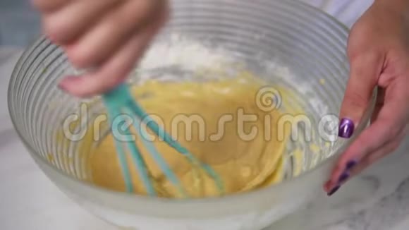 近距离观看女性手混合配料使用搅拌器准备面团在厨房自制食物慢动作视频的预览图