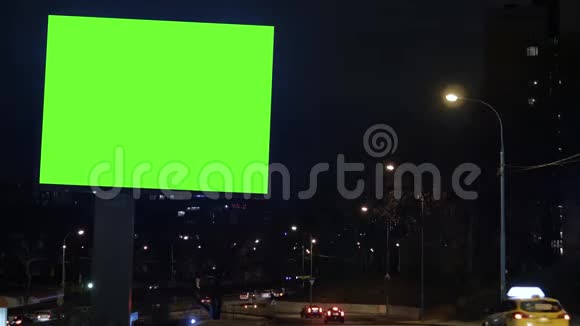 有绿色屏幕的广告牌位于一条繁忙的街道上汽车在晚上移动视频的预览图