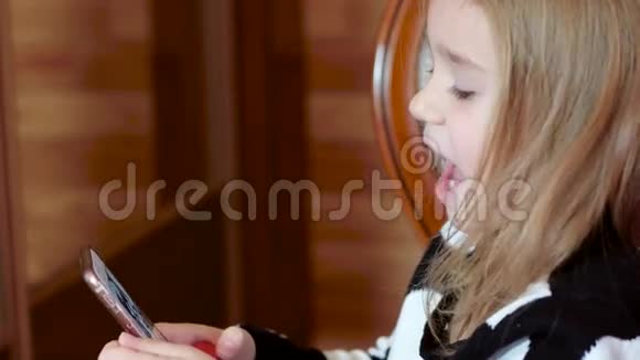 可爱的小女孩玩手机女孩打开手机上的应用程序玩手机游戏说话视频的预览图