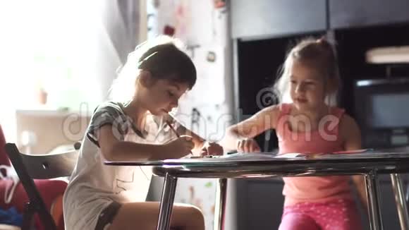 两个小女孩坐在厨房的桌子旁用蜡笔画画视频的预览图