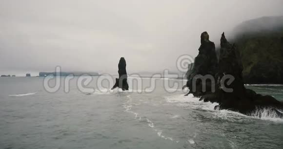 冰岛巨魔脚趾岩石和黑色火山海滩的鸟瞰图直升机离悬崖很近视频的预览图
