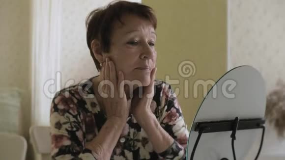 一位老妇人看着镜子里的皱纹舒缓皮肤整形手术和胶原蛋白注射现实视频的预览图