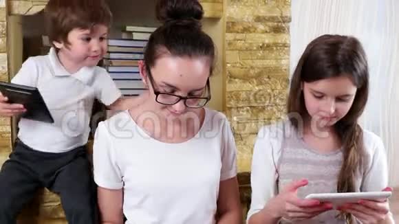 十几岁的女孩和他们的弟弟一起玩电子设备视频的预览图