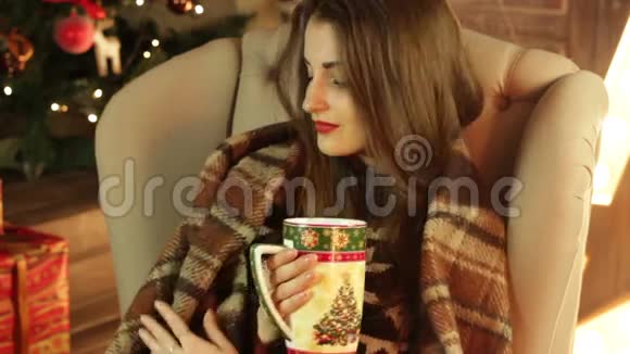 有毯子的女孩坐在椅子上喝圣诞杯的茶视频的预览图