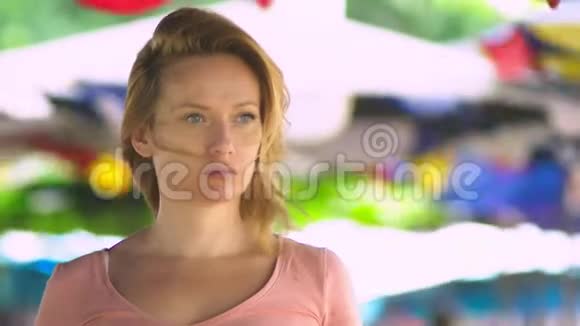 一位金发美女站在一个开放的空间里在一个刮风的日子里专注地看着相机副本视频的预览图