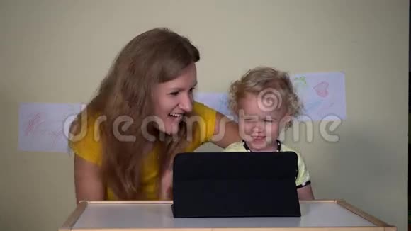 年轻的女人和她的孩子在平板电脑上看有趣的卡通视频的预览图