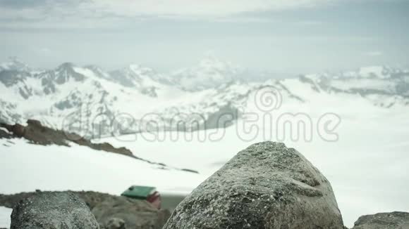 冒险家脚穿皮鞋踩在雪山风景区的岩石上视频的预览图