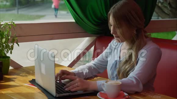 女子在人行道咖啡厅的笔记本电脑上工作视频的预览图