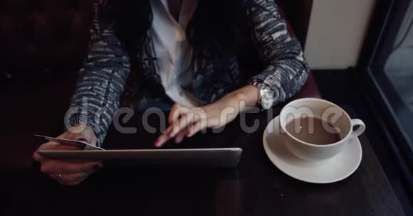 年轻女子在咖啡馆的平板电脑上做网上购物4k视频的预览图